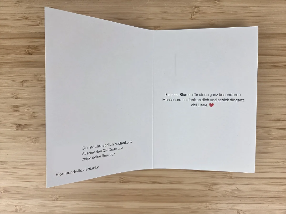 Aufgeklappte Bloom & Wild Grußkarte mit gedrucktem Text und dem Hinweis auf den QR-Code zum Bedanken