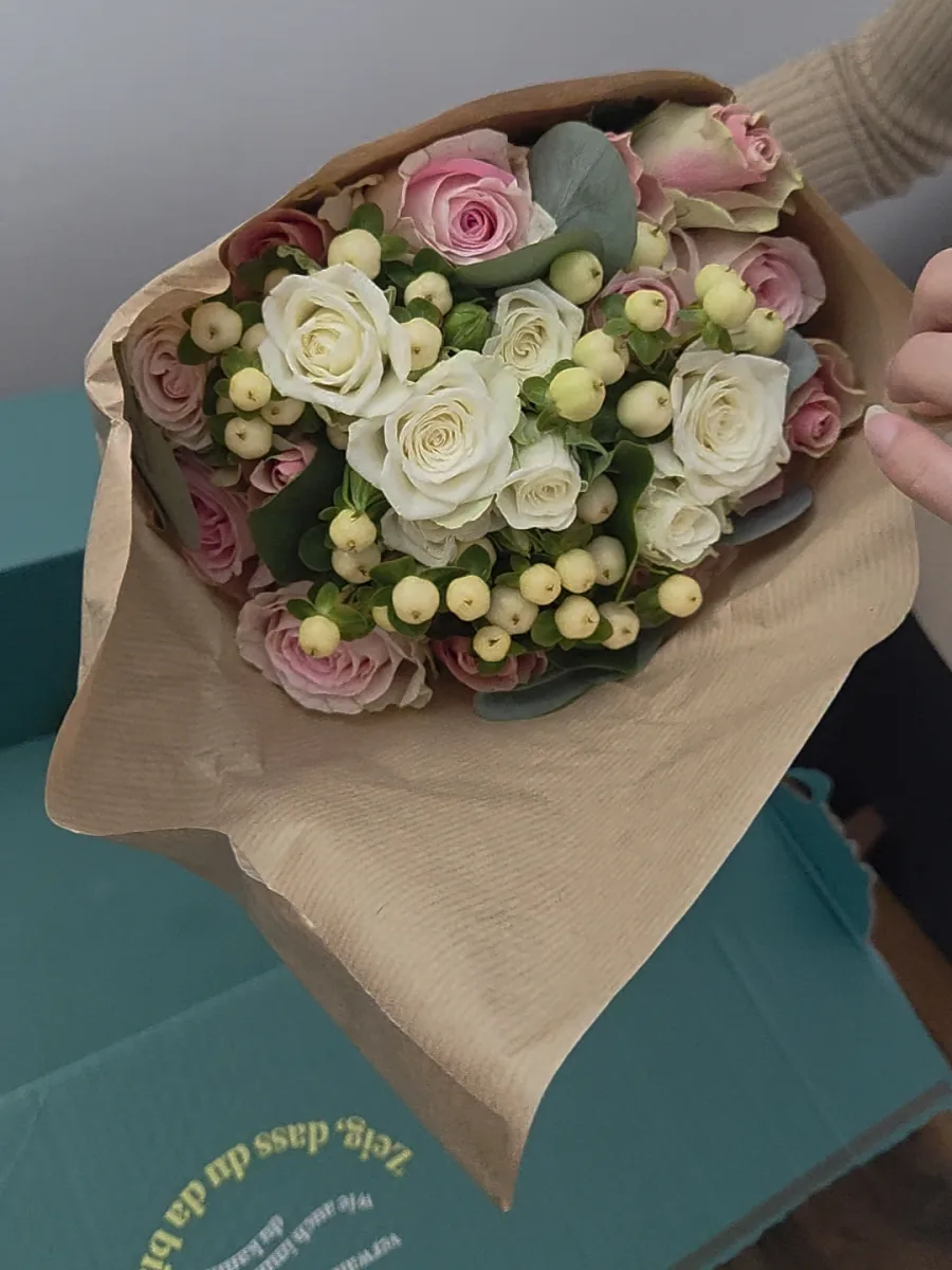 Bloom & Wild Strauß Rosengarten am Liefertag frisch ausgepackt im Packpapier, mit Rosenknospen, weißen Sprührosen und Hypericum-Beeren