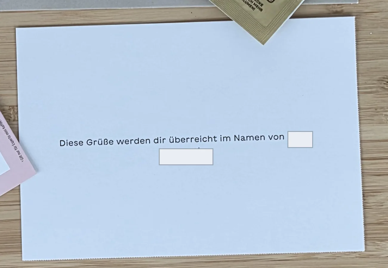 Grußkarte aus dem BLUME2000-Testkauf mit dem Text Diese Grüße werden dir überreicht im Namen von, der Absendername ist abgedeckt