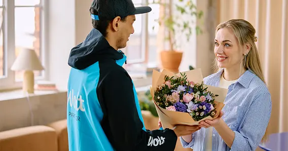Wolt-Fahrer übergibt Blumenstrauß an Kundin – Expresslieferung in 30 bis 60 Minuten