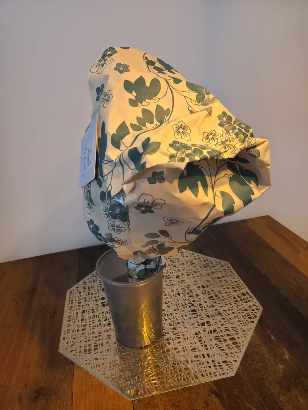 Euroflorist Strauß bei Anlieferung, in floral bedruckte Papierfolie eingewickelt mit angeklebtem Lieferschein, in einer Plastikvase