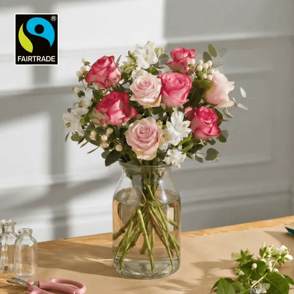 Fairtrade-Strauß Fürsorge von Bloom & Wild mit pinken und rosa Rosen, weißen Blüten und Eukalyptus in einer Glasvase