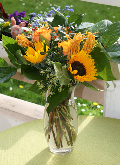 Blumenstrauß Vincent von FloraPrima aus unserem Testkauf, Sonnenblumen mit orangen Rosen in einer Glasvase